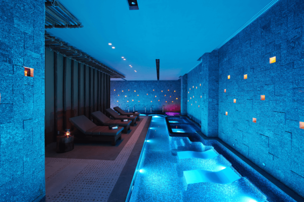 spa pool lit up with blue lights and lounge chairs